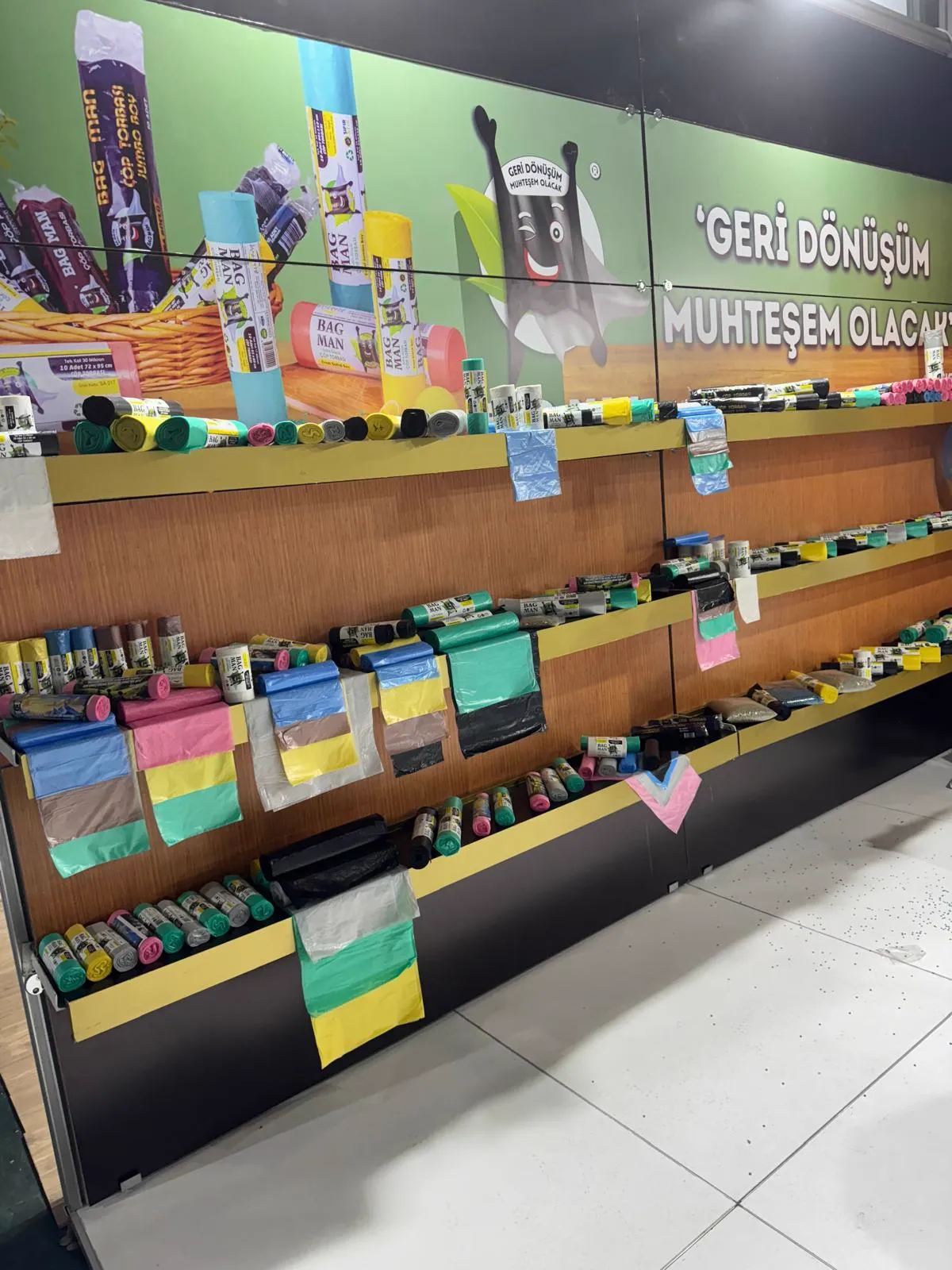 Retail display shelf with plastic bag rolls